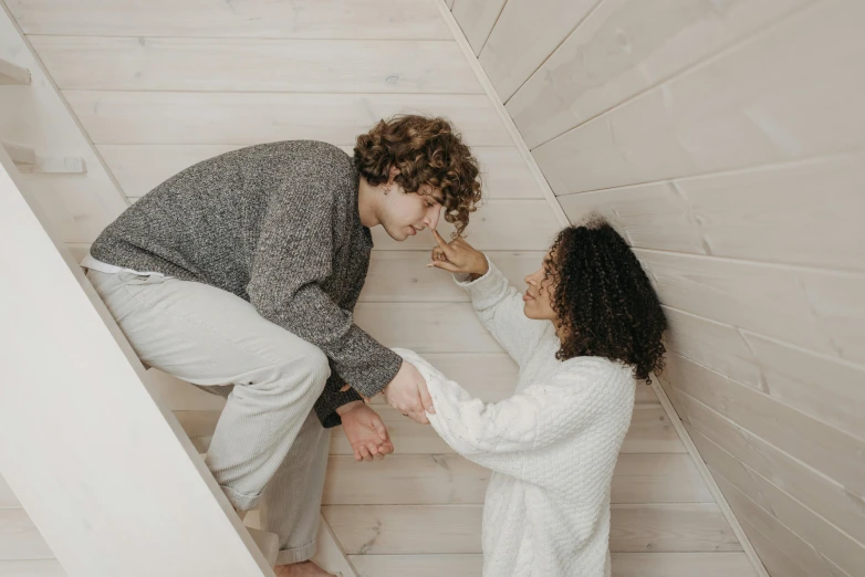 a man and a woman shaking hands in a room, trending on pexels, stairs, playful pose, in an attic, background image