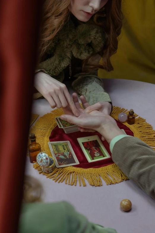 a couple of people that are sitting at a table, renaissance, channeling mana, holding hands, red and gold cloth, cards