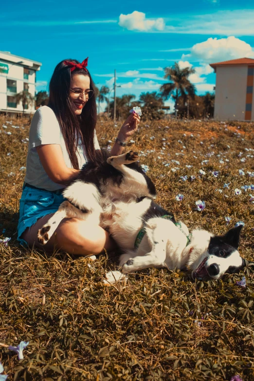 a woman sitting on the ground with two dogs, by Julia Pishtar, pexels contest winner, pop art, sitting in a field of cannabis, siberian husky, dua lipa, a still of a happy