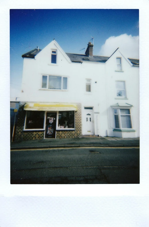 a white building sitting on the side of a road, a polaroid photo, by Bedwyr Williams, private press, shop front, 1990s photograph, wales, conor walton