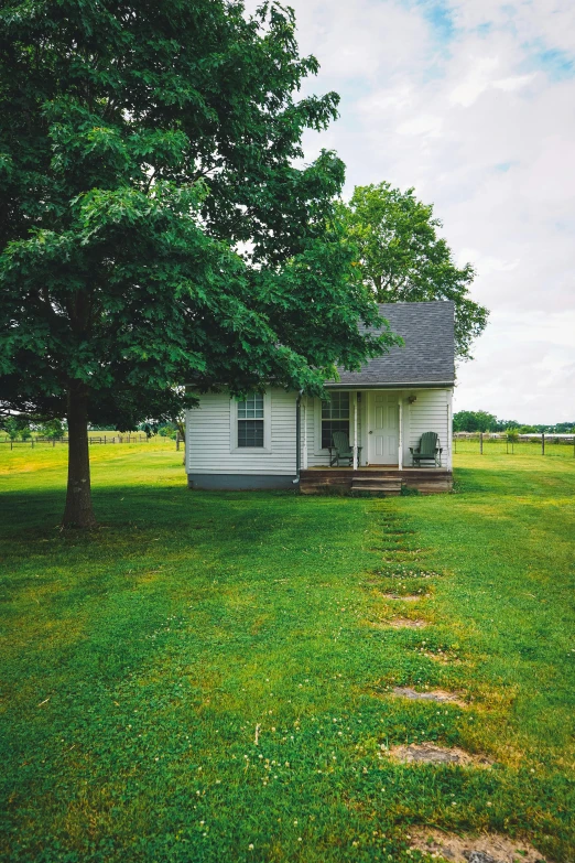 a small white house sitting on top of a lush green field, redneck country, square, 2019 trending photo, ground level view