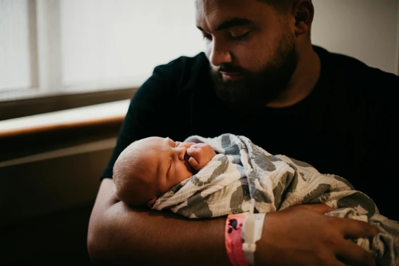 a man holding a baby in his arms, by Matt Cavotta, pexels contest winner, te pae, bowater charlie and brom gerald, the birth, thumbnail