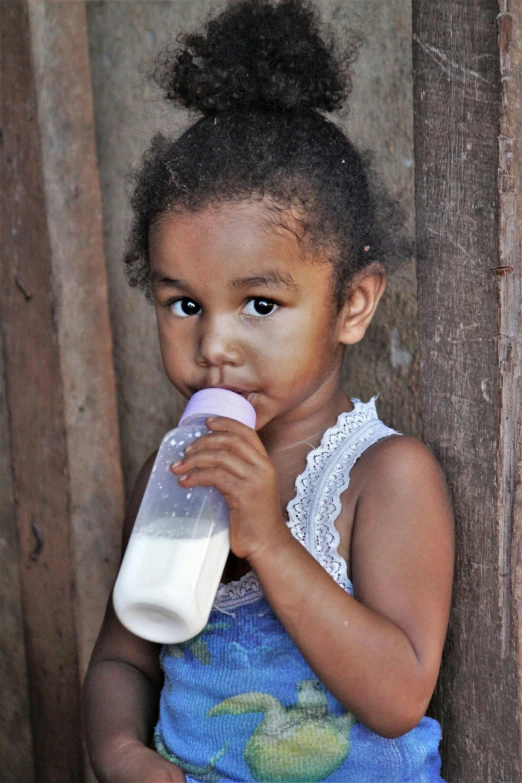 a little girl holding a bottle of milk, brown skinned, malika favre, slide show, small