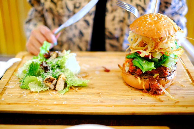 a person sitting at a table with a sandwich and salad, by Julia Pishtar, unsplash, hamburger mix jellyfish, on a wooden tray, melbourne, pulled pork sandwich