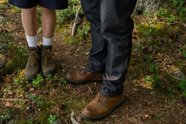 a man and a woman standing next to each other in the woods, by Eero Järnefelt, unsplash, photorealism, jeans and boots, detailed shot legs-up, photograph taken in 2 0 2 0, rugged ranger