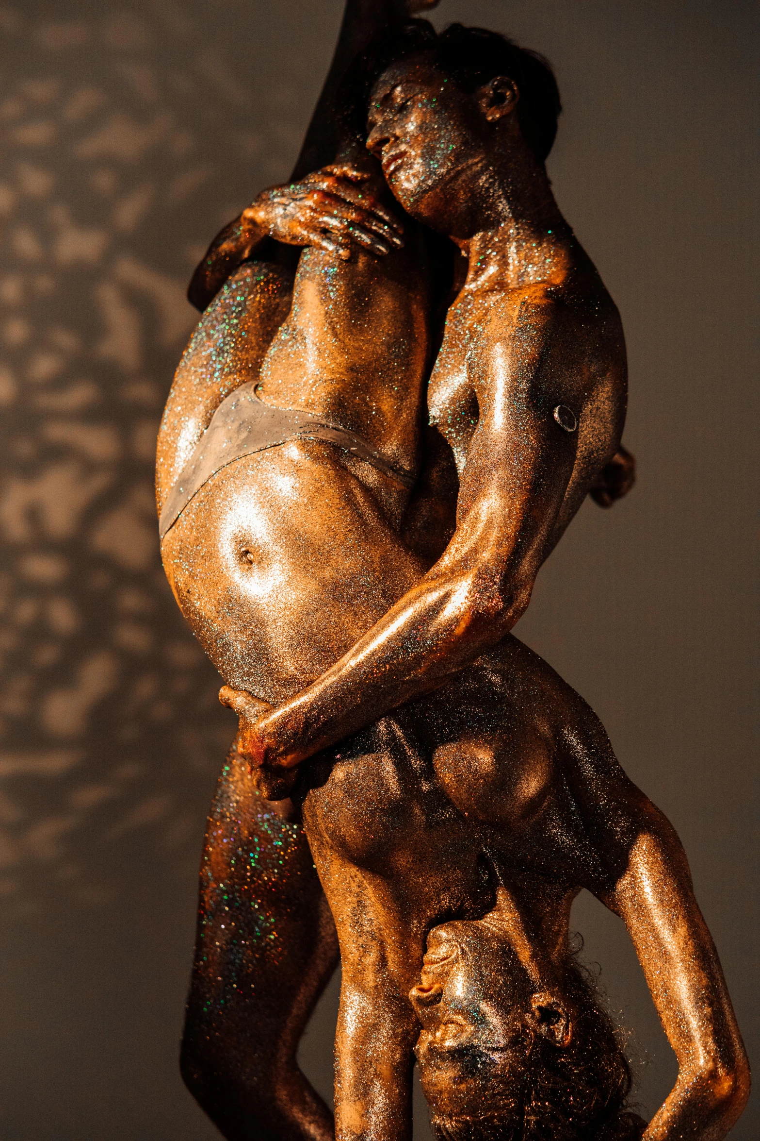 a bronze statue of a man holding a woman, a bronze sculpture, inspired by William Zorach, golden dappled dynamic lighting, muscular men entwined together, made of wax and oil, high texture detail