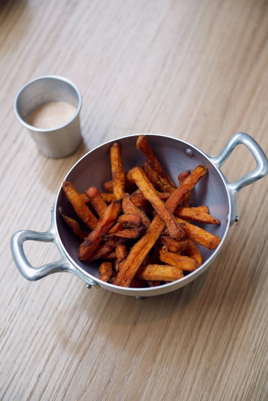 a bowl of fries sitting on top of a wooden table, orange metal ears, handheld, crisps, cream of the crop