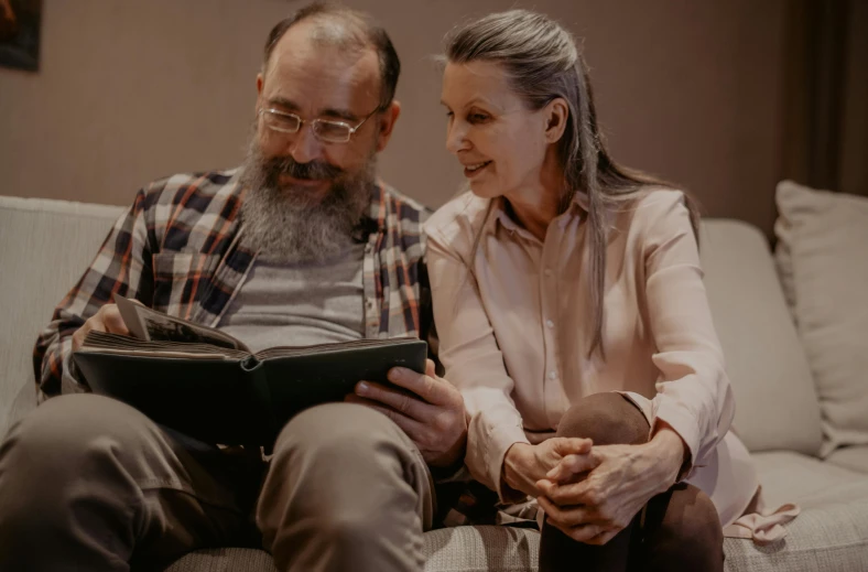 a man and woman sitting on a couch reading a book, a portrait, pexels contest winner, healthcare, profile image, maintenance photo, looking to the right