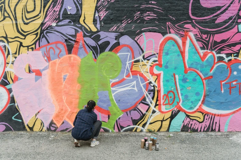 a person sitting on a skateboard in front of a graffiti wall, graffiti art, by Tom Bonson, trending on unsplash, graffiti, multicoloured, facing away, work in progress, in chippendale sydney