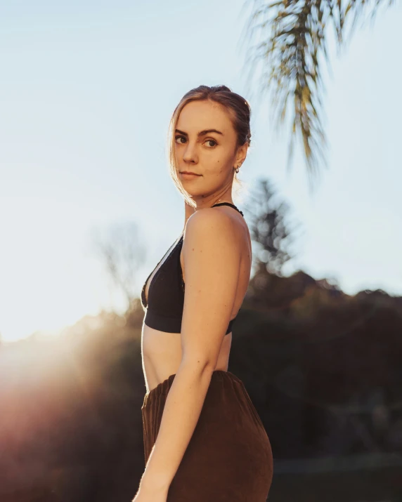 a woman standing in front of a palm tree, sports bra, at the golden hour, profile image, sydney sweeney