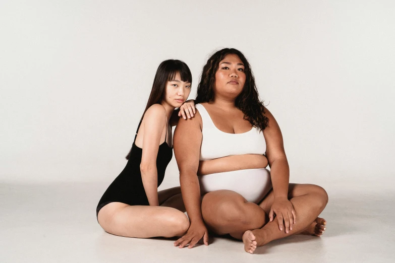 a couple of women sitting next to each other, thick body, half asian, two skinny figures, skin tones