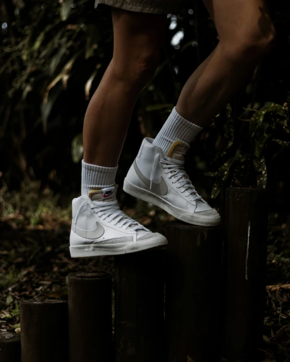 a person standing on top of a wooden post, inspired by Elsa Bleda, unsplash contest winner, renaissance, wearing white sneakers, in a jungle, white and gold, high arches