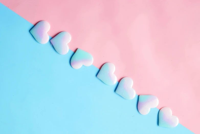 a row of marshmallows on a pink and blue background, by Rachel Reckitt, trending on pexels, aestheticism, hearts symbol, enamel, lgbtq, sweet artpiece