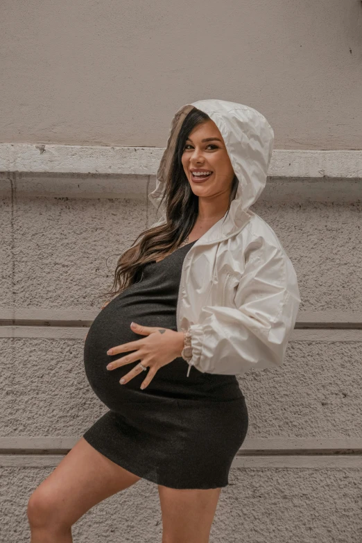 a pregnant woman in a white jacket and black skirt, by Robbie Trevino, pexels contest winner, happening, sofia vergara, black haired girl wearing hoodie, girl in raincoat, birth