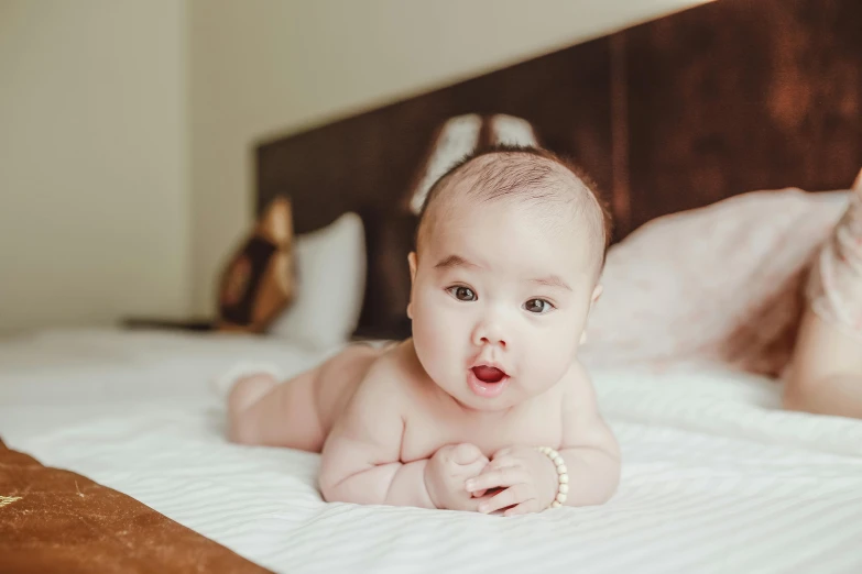 a close up of a baby laying on a bed, pexels contest winner, happening, darren quach, graceful face, highly polished, surprised