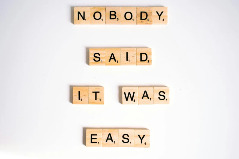 scrabbles spelling the words nobody said it was easy, a poster, unsplash, modernism, set against a white background, background image, a wooden, addiction