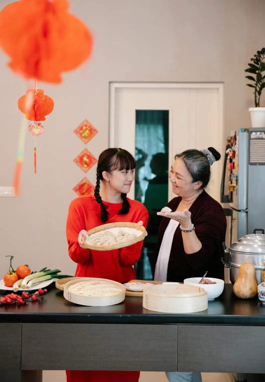 a couple of women standing next to each other in a kitchen, inspired by Cui Bai, happening, offering a plate of food, steamed buns, premium quality, trending photo