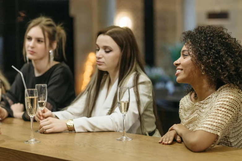 a group of women sitting at a table with wine glasses, on a table