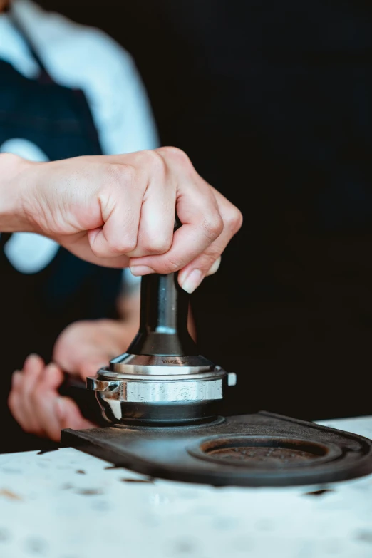 a close up of a person pressing a button on a stove, an etching, by Matthias Stom, trending on unsplash, ancient coffee machine, detailed product image, partially cupping her hands, fine dining