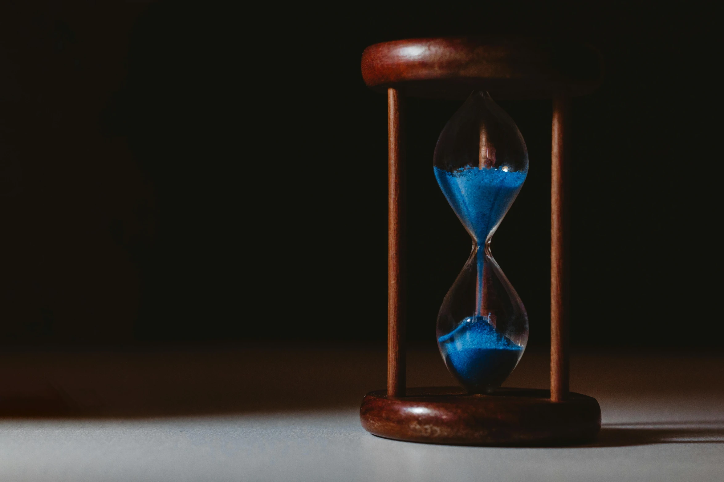 an hourglass sitting on top of a table, pexels contest winner, hyperrealism, blue sand, timeline nexus, politics, wooden