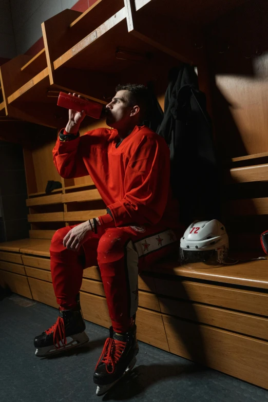 a man sitting on a bench drinking from a bottle, full ice hockey goalie gear, iu, locker room, promo image