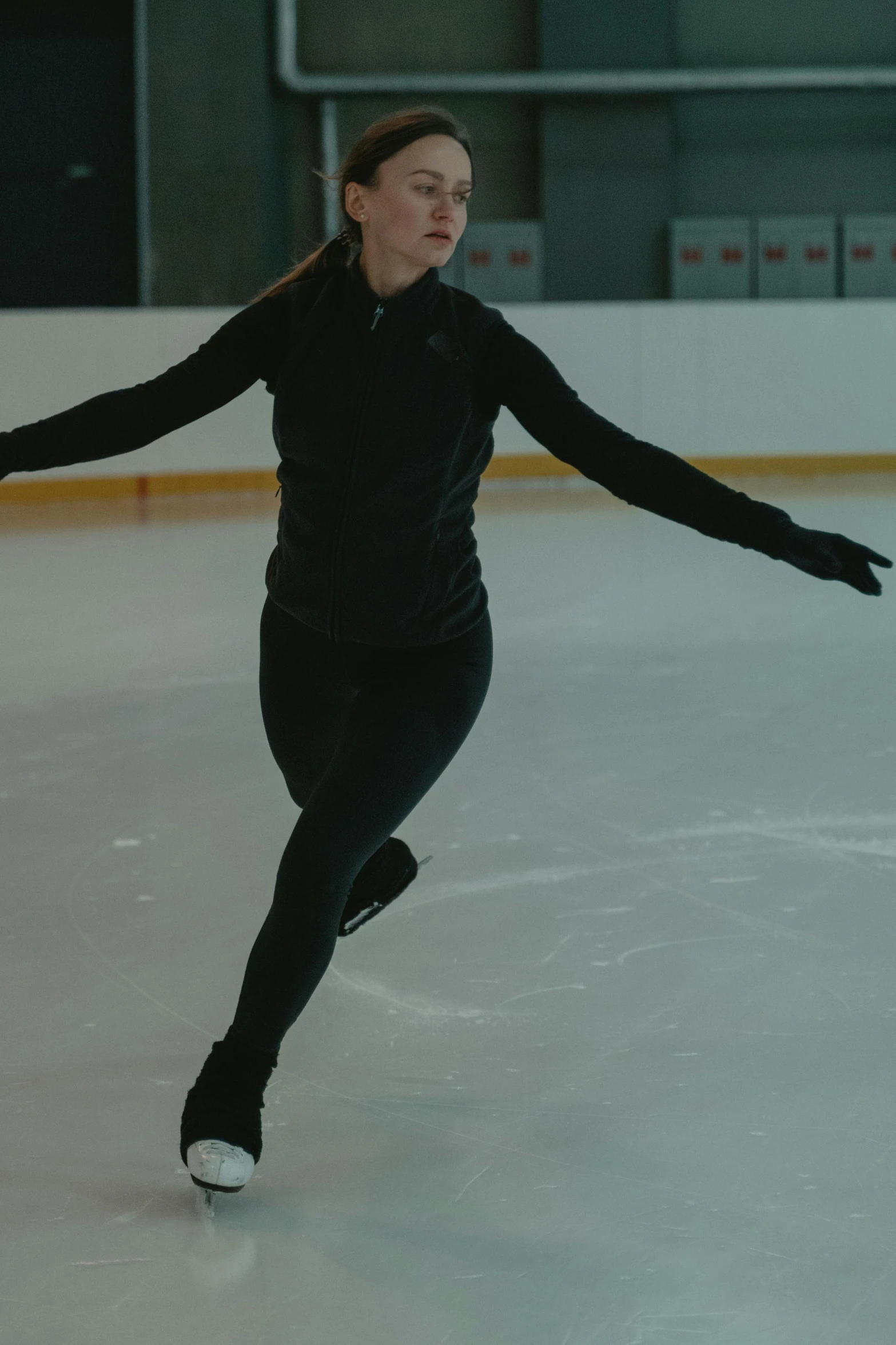 a female figure skating on an ice rink, wearing a track suit, black undersuit, cinematic still, promo image