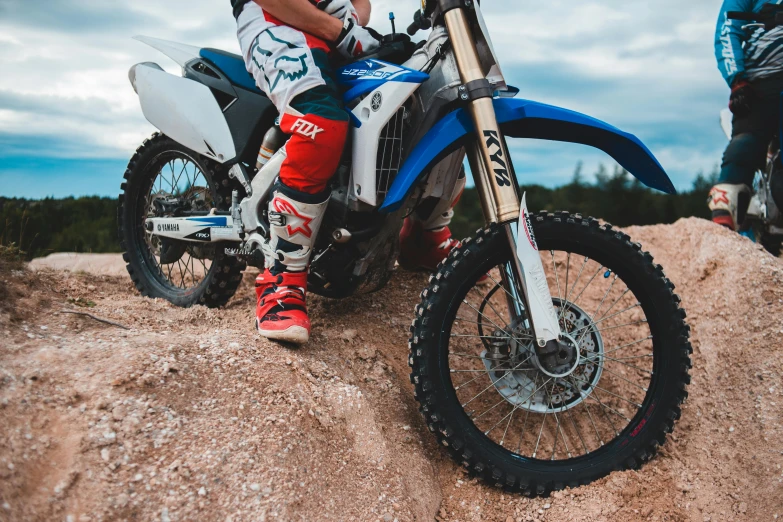 a man riding on the back of a dirt bike, unsplash, figuration libre, close-up on legs, avatar image, blue or red, sitting on a rock