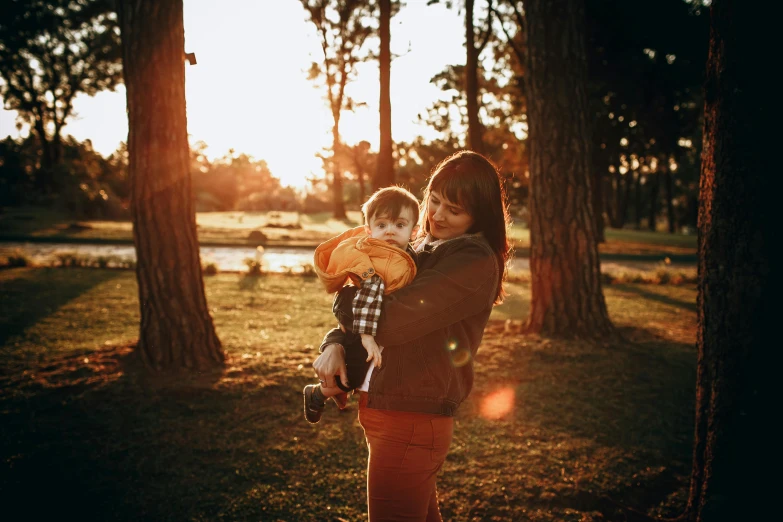 a woman holding a child in her arms, pexels contest winner, sydney park, warm golden backlit, avatar image, picnic