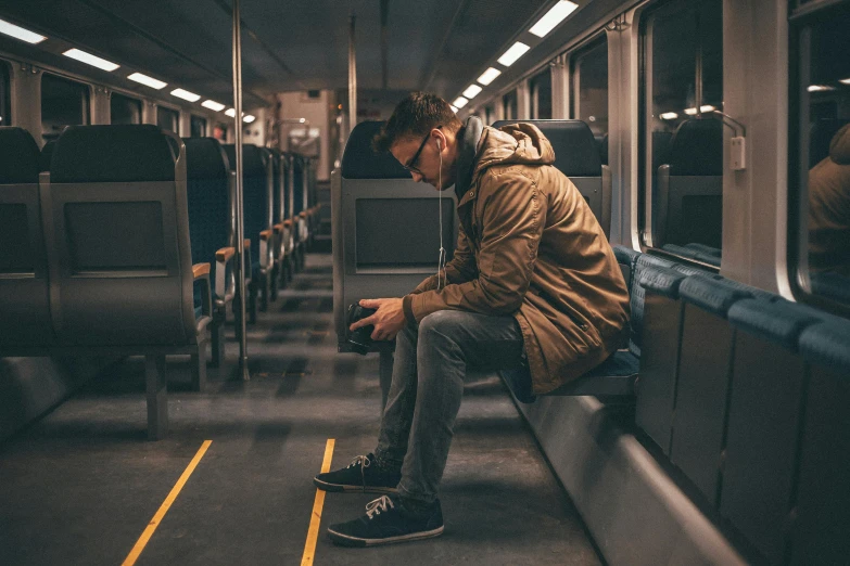a man sitting on a train looking at his cell phone, pexels contest winner, lonely and sad, sitting on bent knees, public bus, australian