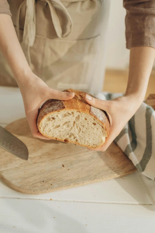 a person holding a loaf of bread on a cutting board, by Arthur Pan, unsplash, story, with a soft, french, cake