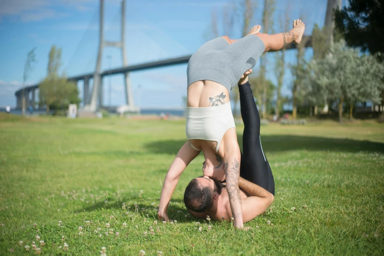 a man and a woman doing a handstand in a park, by Romain brook, arabesque, portait image