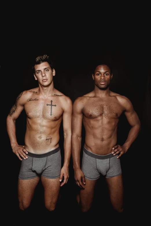 a couple of men standing next to each other, a colorized photo, by Jessie Alexandra Dick, unsplash, black underwear, on a black background, religious, instagram photo