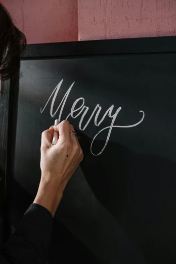 a woman writing merry on a blackboard, by Carey Morris, pexels, calligraphy, thumbnail, low detail, 1 6 x 1 6