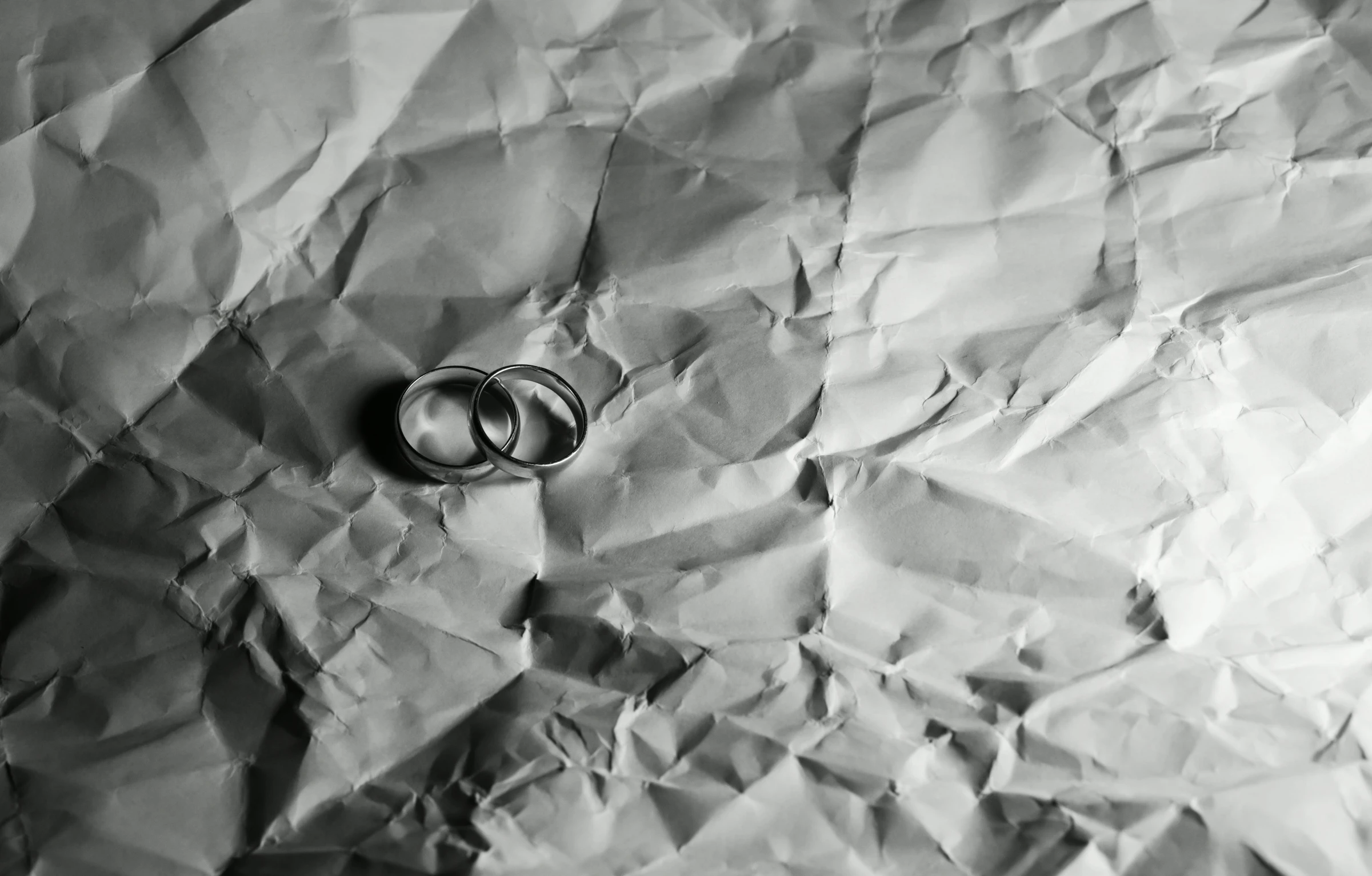 a couple of wedding rings sitting on top of a piece of paper, a black and white photo, pexels, minimalism, paper crumpled texture, 15081959 21121991 01012000 4k, made of silk paper, video