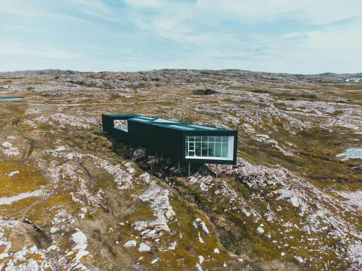 a black house sitting on top of a hill, by Jesper Knudsen, pexels contest winner, visual art, inuit heritage, helicopter view, conde nast traveler photo, symmetrical outpost