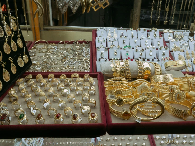 a display case filled with lots of gold jewelry, a photo, street market, red white and gold color scheme, 3 4 5 3 1, fan favorite