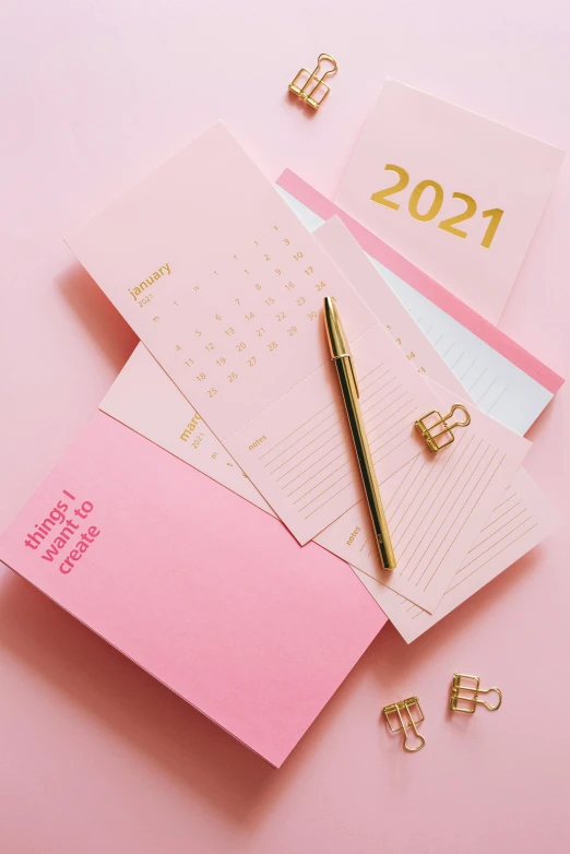 a pink notebook with a pen sitting on top of it, by Julia Pishtar, happening, gold theme, contest winner 2021, cleanest image, female calendar