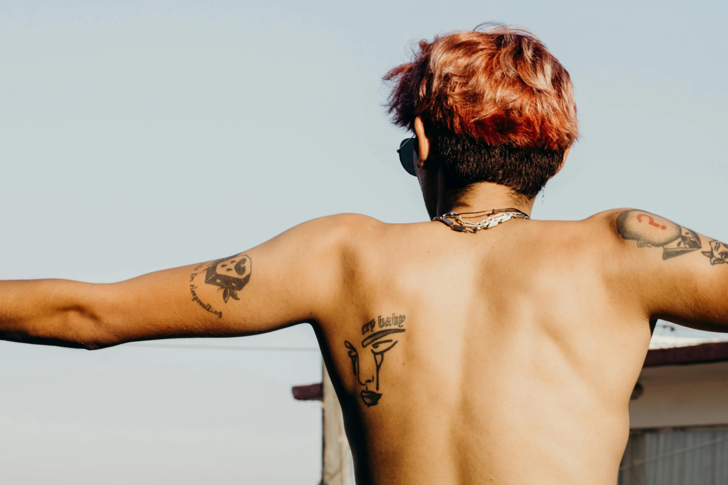 a man with a tattoo on his back, a tattoo, trending on pexels, red haired teen boy, tan skin, background image, looking at the sky