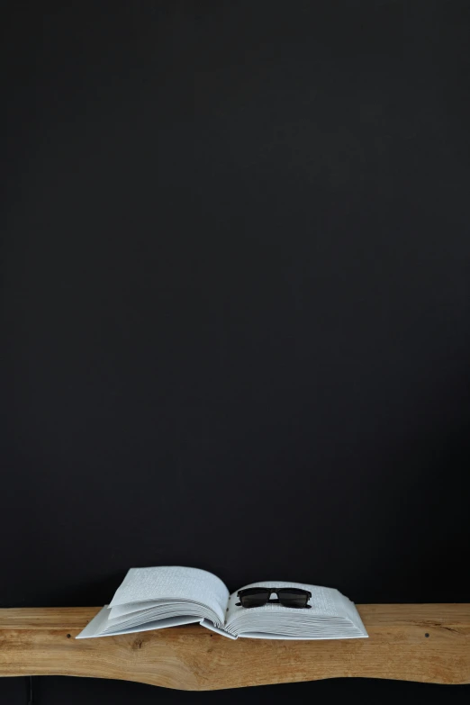 an open book sitting on top of a wooden table, by James Morris, postminimalism, blackboard, black, panel of black, image