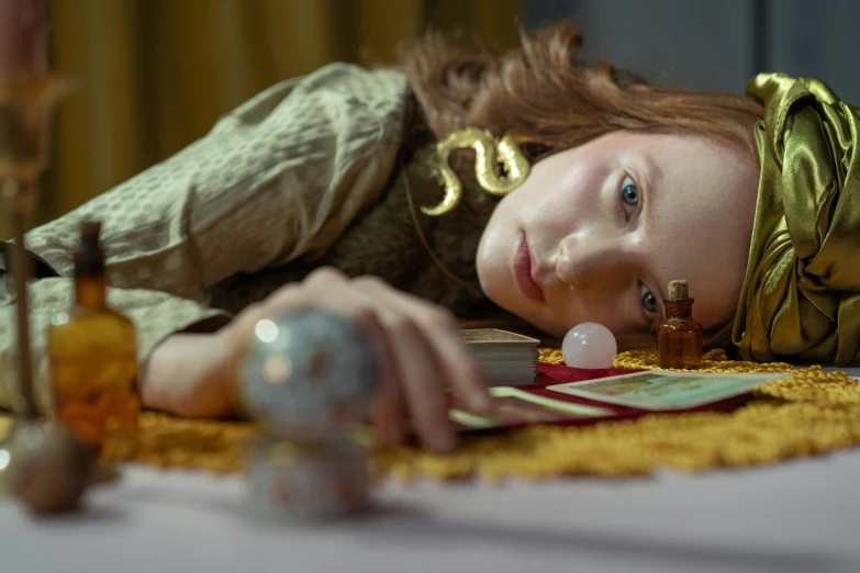 a close up of a person laying on a table, a portrait, inspired by John Collier, magic realism, miss aniela, eleanor tomlinson, fortune teller, demna gvasalia