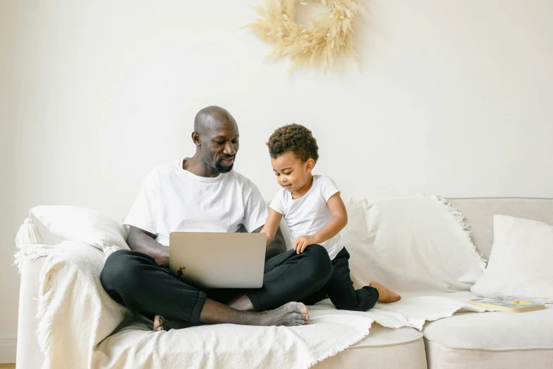 a man and a child sitting on a couch with a laptop, pexels contest winner, brown and cream color scheme, toddler, black people, maintenance