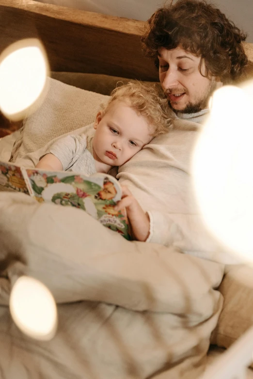 a man reading a book to a child on a bed, pexels, lights on, a blond, promo image, soft texture