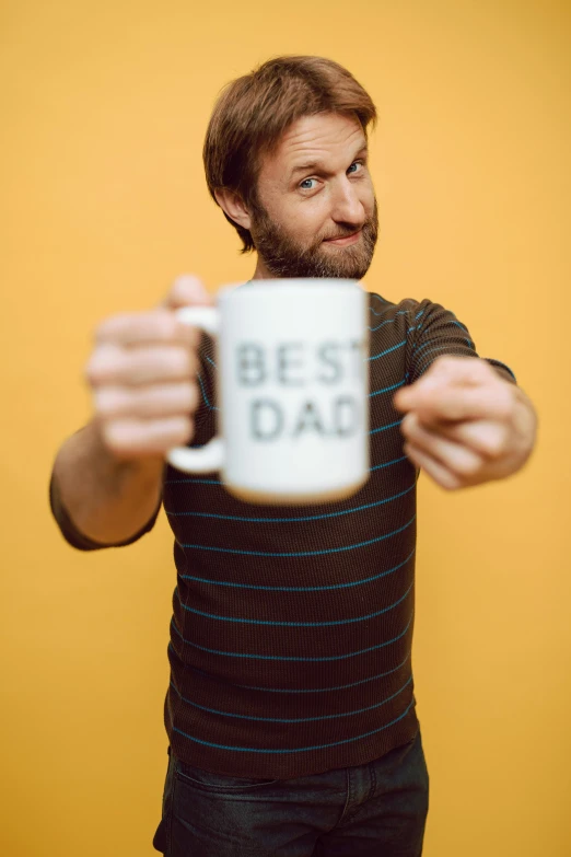 a man holding a coffee mug with the words best dad on it, by Everett Warner, dau-al-set, charlie cox, press shot, minn, 1 0