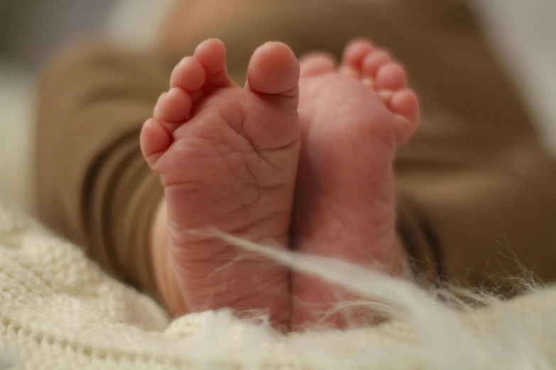 a close up of a baby's feet on a blanket, pexels, ultra realistic render, brown, extra high resolution, ultra realistic