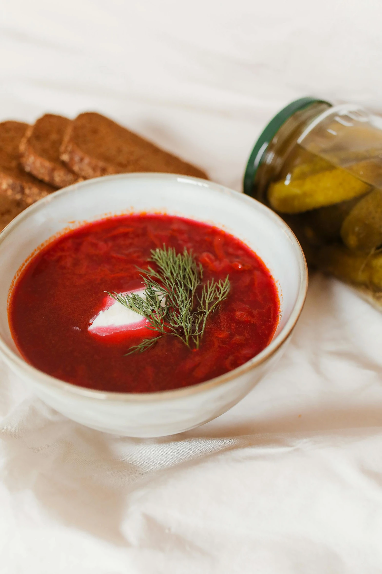 a bowl of soup next to crackers and a jar of pickles, by Ilya Ostroukhov, beets, red square, bright red, vintage vibe