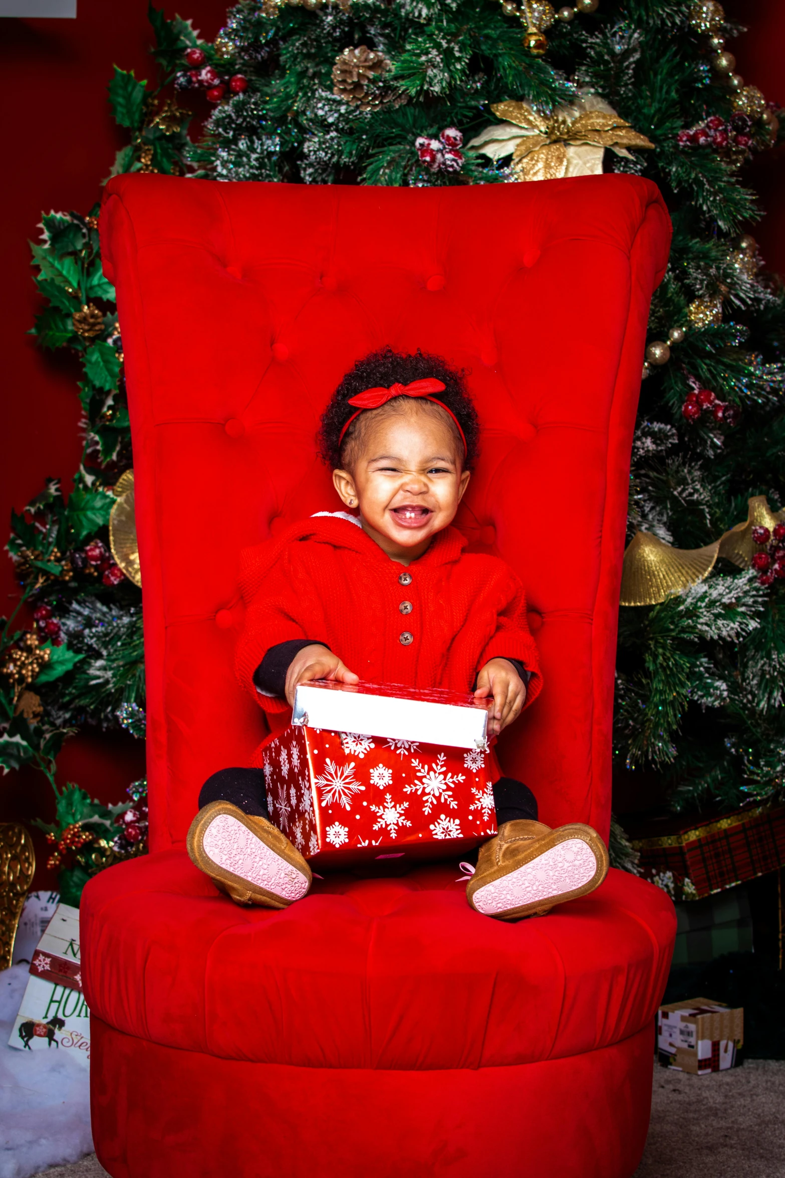 a little girl sitting on a red chair in front of a christmas tree, a portrait, by Dorothy Bradford, shutterstock contest winner, youthful taliyah, riyahd cassiem, on her throne, she is smiling and excited