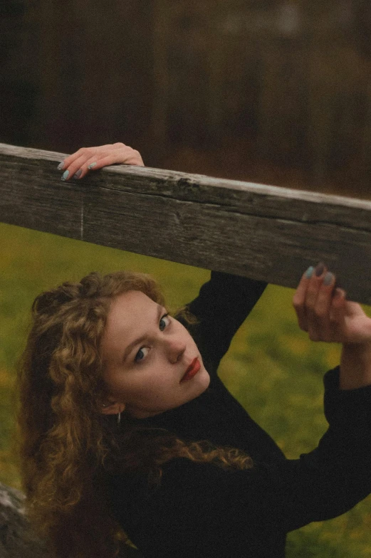 a woman leaning on a wooden fence in a field, an album cover, inspired by Annie Leibovitz, unsplash, renaissance, pale skin curly blond hair, ((portrait)), around 1 9 years old, color photograph portrait 4k