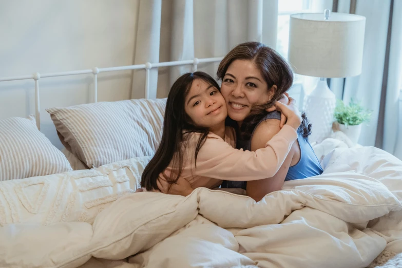 a woman hugging a little girl on top of a bed, pexels contest winner, asian woman, 64x64, bedhead, confident looking