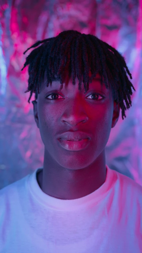 a young man with dreadlocks wearing a white t - shirt, an album cover, inspired by Xanthus Russell Smith, trending on pexels, realism, glowing magenta face, black teenage boy, adut akech, finn wolfhard