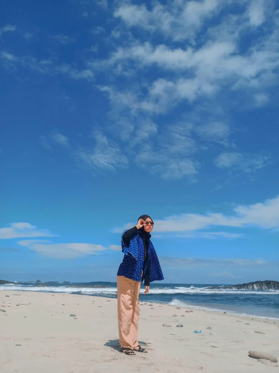 a man standing on top of a sandy beach, wearing a blue jacket, 📷 mungojerrie and rumpleteazer, full body shot!!, bella poarch